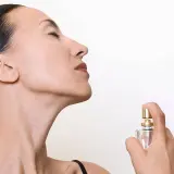 Mujer disfrutando el aroma de un perfume, quizás un ikiru de Mercadona, con los ojos cerrados.