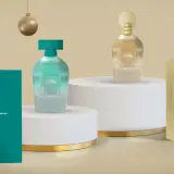 Dos perfumes "My Soul Enchanted" en tonos turquesa y dorado, junto a su caja, evocan la esencia de Mercadona.