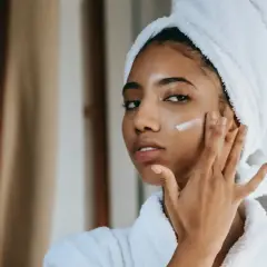 Mujer con toalla en la cabeza aplicándose crema para combatir la piel seca.
