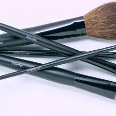 Un conjunto de brochas de maquillaje negras, etiquetadas como "blusher", "blender", "eyeshadow", "powder" y "make-up", listas para aprender como limpiar brochas de maquillaje.