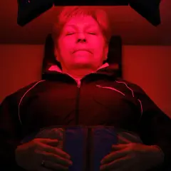 Mujer relajada bajo luz roja, experimentando los beneficios de la terapia de luz para el bienestar.
