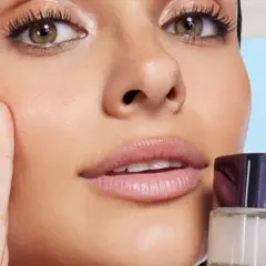 Una mujer se aplica crema en el rostro, buscando minimizar los poros abiertos y lograr una piel radiante.