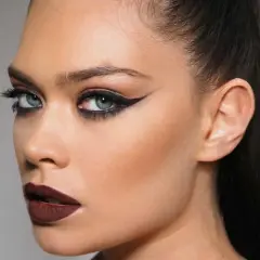 Ojos dramáticos con delineado cat eye y labios oscuros, resaltando el uso de kohl para una mirada intensa.