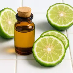 Aceite esencial de bergamota que es, junto a rodajas y una fruta entera de esta cítrica fragante.