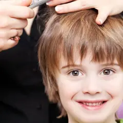 Un niño sonriente recibe unos cortes de pelo modernos.