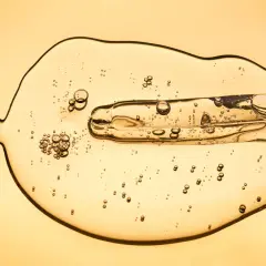 Gota dorada con burbujas, como si fueran exosomas que son pequeñas vesículas.