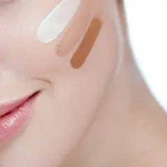 Prueba de tonos de corrector en la mejilla de una mujer.