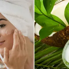 Mujer aplicándose crema en la cara junto a un coco y hojas verdes.