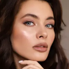 Primer plano de una mujer con cabello castaño oscuro y ojos azules. Su piel luce radiante, resaltando la belleza natural de la melanina.