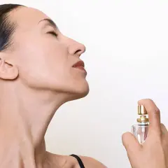 Mujer disfrutando el aroma de un perfume, quizás un ikiru de Mercadona, con los ojos cerrados.