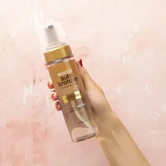 Mano sostiene botella de mousse autobronceador Deliplus de Mercadona. Bronceado natural y uniforme.