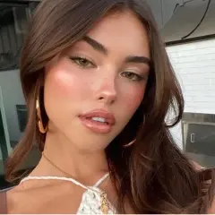 Mujer joven con cabello castaño y maquillaje natural, luciendo un **clean look** con mejillas sonrosadas y labios brillantes.