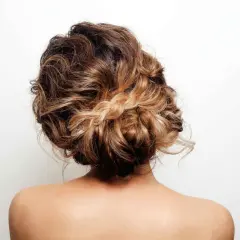 Recogido pelo rizado informal con trenza central, ideal para un look desenfadado y chic.