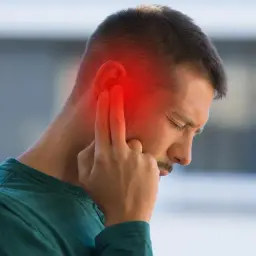 Hombre con dolor de oído, señalando la zona afectada con un halo rojo. Podrían ser sabañones en las orejas por el frío.