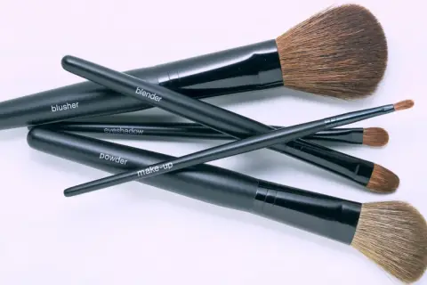 Un conjunto de brochas de maquillaje negras, etiquetadas como "blusher", "blender", "eyeshadow", "powder" y "make-up", listas para aprender como limpiar brochas de maquillaje.
