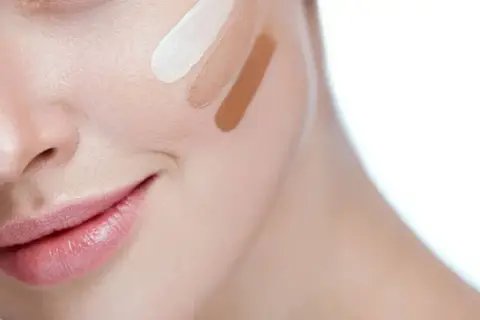 Prueba de tonos de corrector en la mejilla de una mujer.