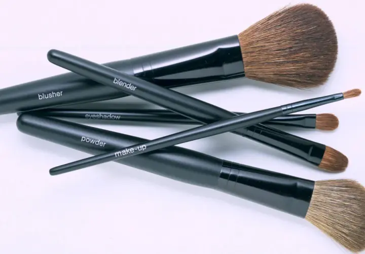 Un conjunto de brochas de maquillaje negras, etiquetadas como "blusher", "blender", "eyeshadow", "powder" y "make-up", listas para aprender como limpiar brochas de maquillaje.