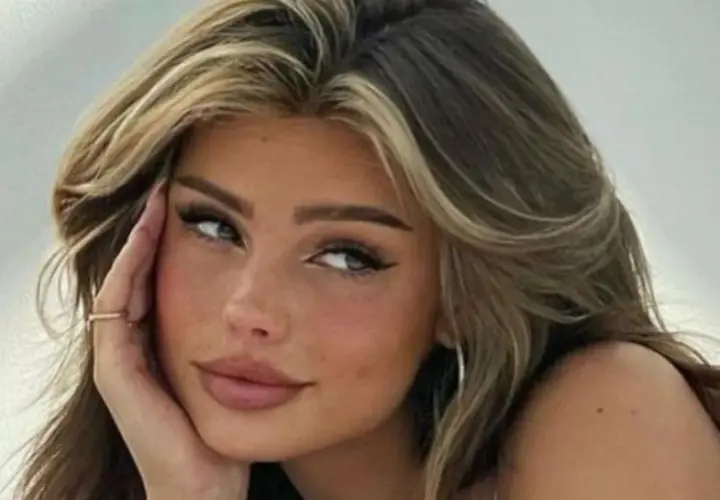 Primer plano de una joven con cabello castaño y rubio, con baby hairs peinados hacia atrás y un delineado de ojos dramático.