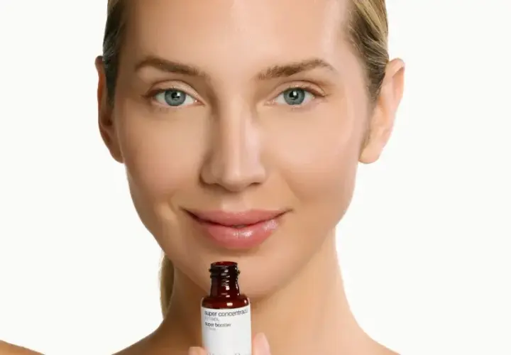 Mujer sonríe sosteniendo un frasco de sérum de retinol. Descubre para qué sirve el retinol y cómo puede mejorar tu piel.