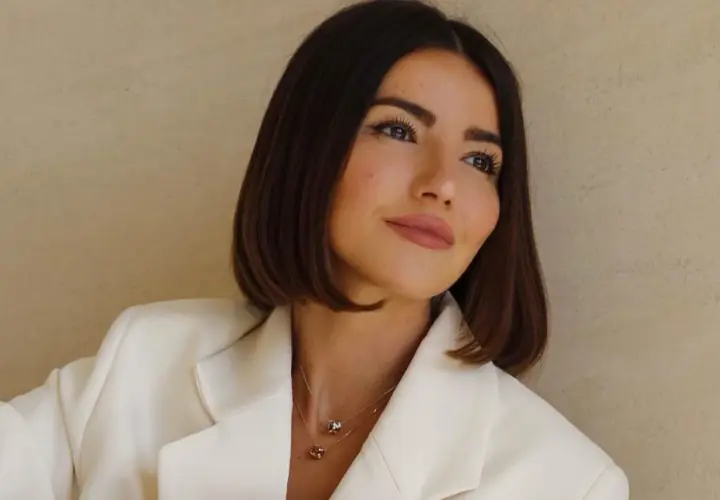 Mujer con un corte de pelo **italian bob**, blazer blanco y collares delicados.