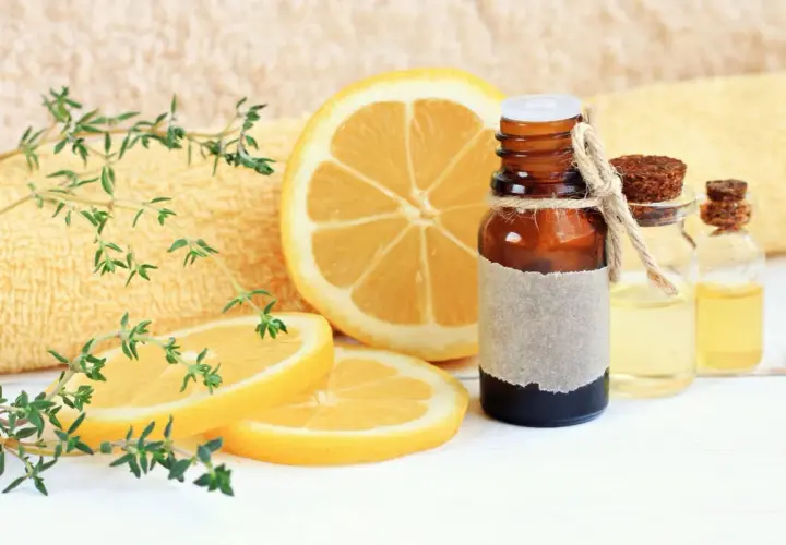 Aceite esencial de limón, con rodajas de limón y ramitas de tomillo. El limoneno es un componente clave.
