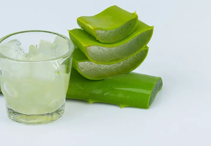 Un vaso con trozos de aloe vera y hojas cortadas apiladas, listas para usar.