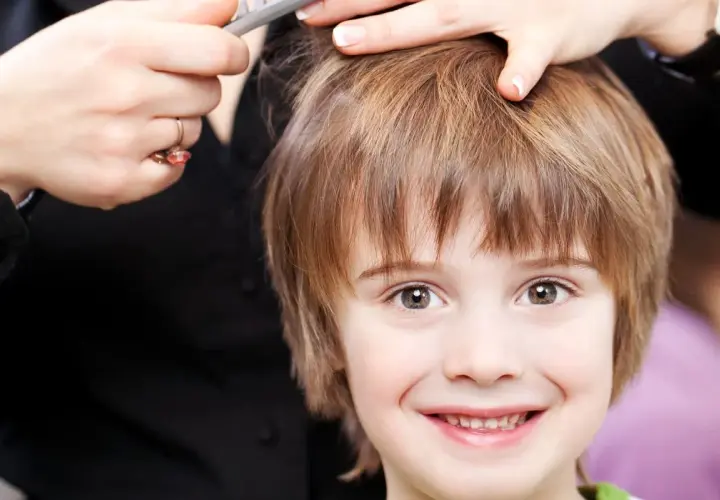 Un niño sonriente recibe unos cortes de pelo modernos.