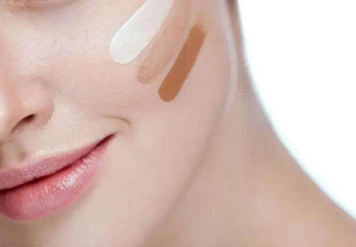 Prueba de tonos de corrector en la mejilla de una mujer.