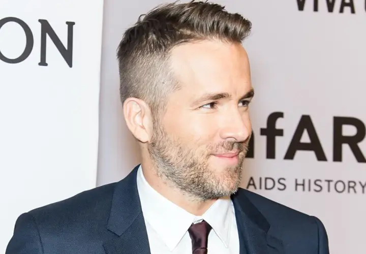 Ryan Reynolds luce un corte de pelo moderno con degradado hombre, barba cuidada y traje oscuro.