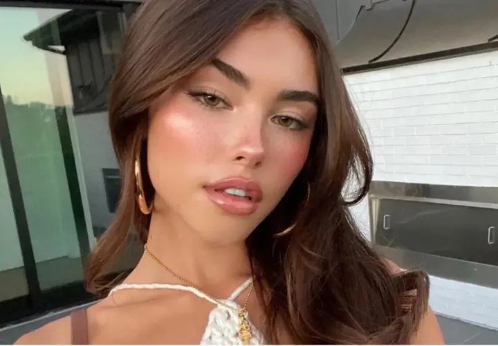 Mujer joven con cabello castaño y maquillaje natural, luciendo un **clean look** con mejillas sonrosadas y labios brillantes.