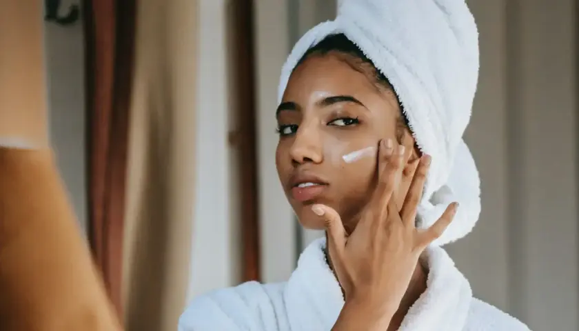 Mujer con toalla en la cabeza aplicándose crema para combatir la piel seca.