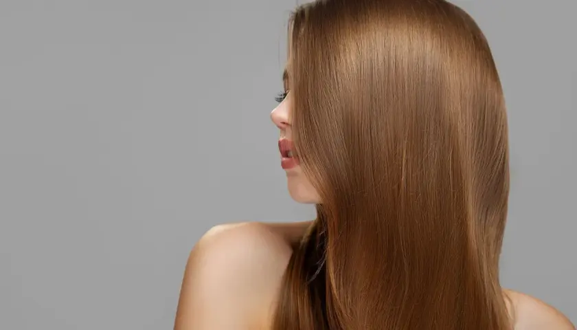 Mujer con cabello largo y liso de tono castaño claro, con reflejos dorados.