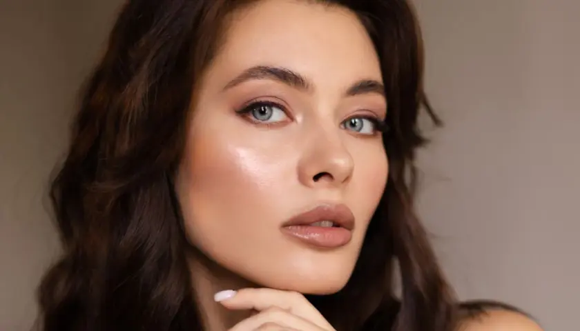 Primer plano de una mujer con cabello castaño oscuro y ojos azules. Su piel luce radiante, resaltando la belleza natural de la melanina.