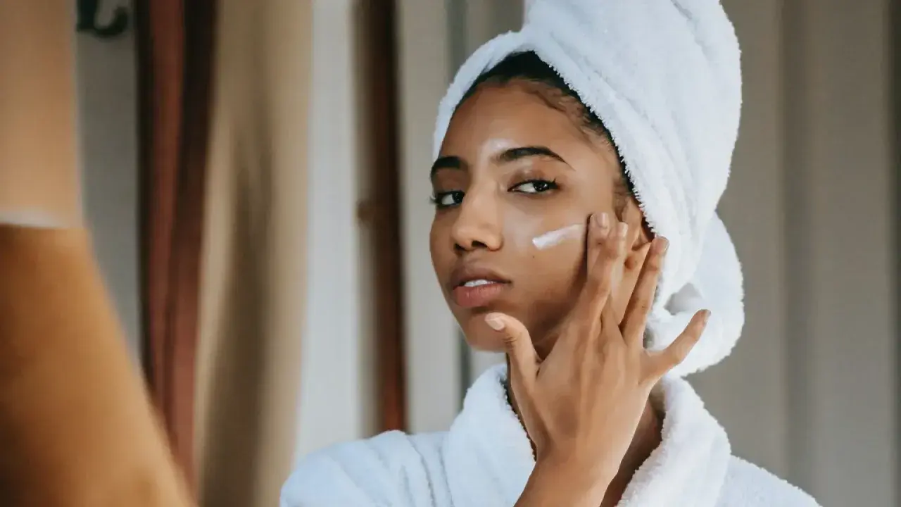 Mujer con toalla en la cabeza aplicándose crema para combatir la piel seca.