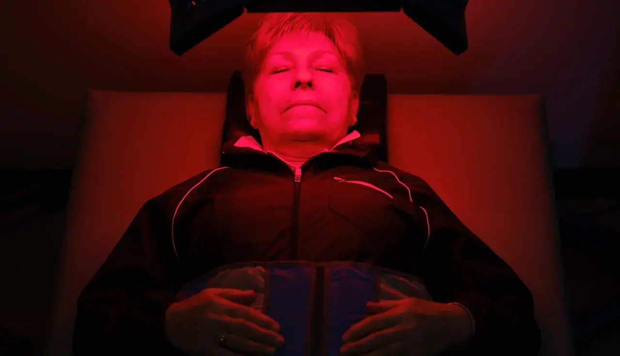 Mujer relajada bajo luz roja, experimentando los beneficios de la terapia de luz para el bienestar.