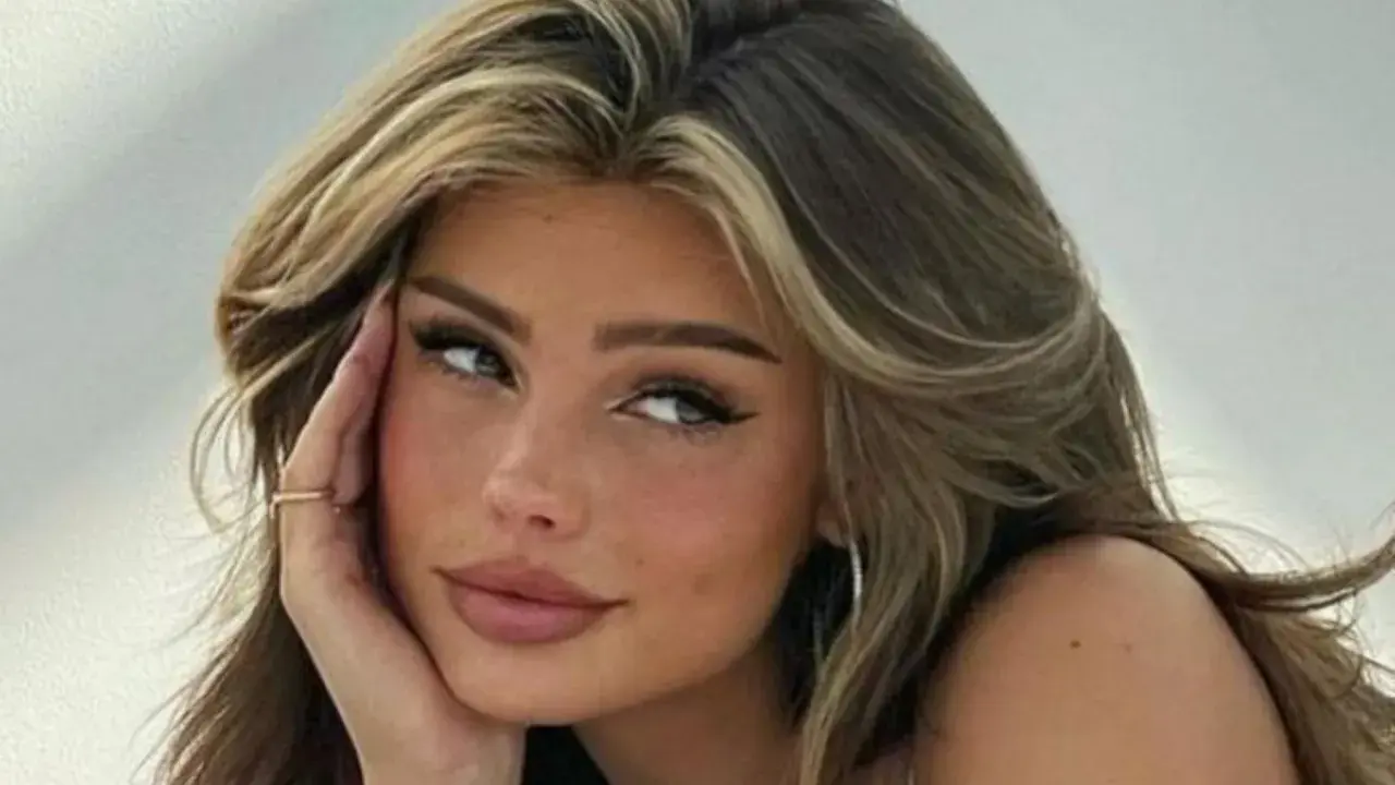 Primer plano de una joven con cabello castaño y rubio, con baby hairs peinados hacia atrás y un delineado de ojos dramático.