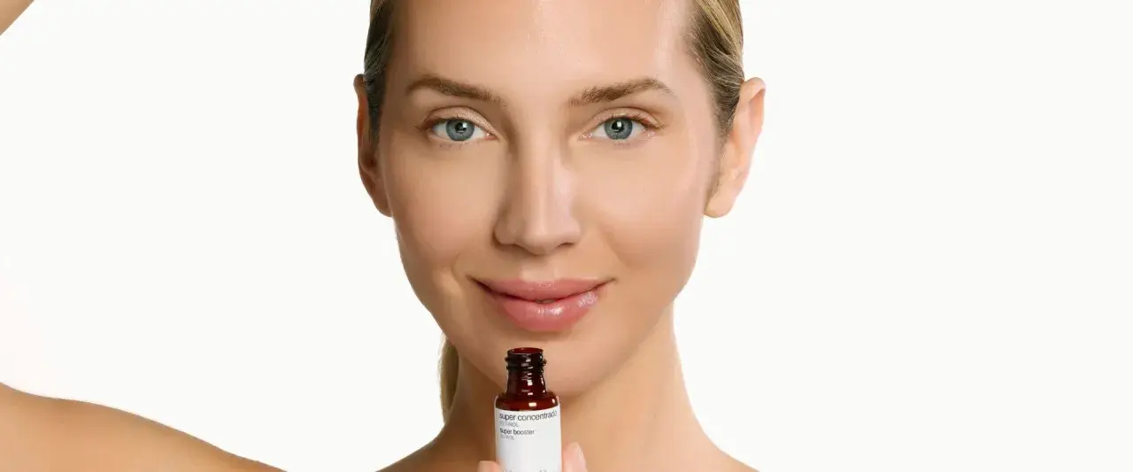 Mujer sonríe sosteniendo un frasco de sérum de retinol. Descubre para qué sirve el retinol y cómo puede mejorar tu piel.