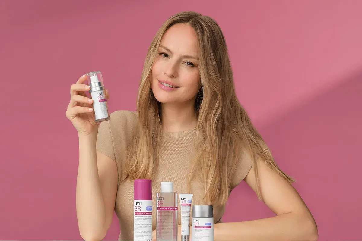 Mujer sonriente con productos Leti SR, ideales para el cuidado de la piel sensible.