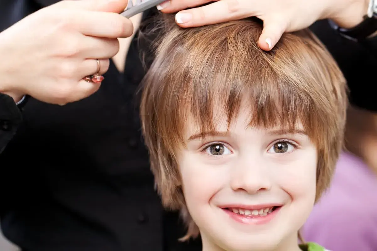 Un niño sonriente recibe unos cortes de pelo modernos.
