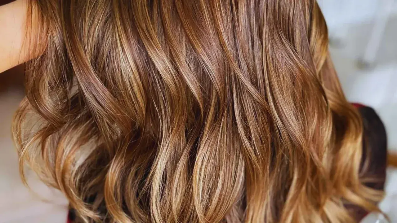 Cabello castaño con mechas rubias que le dan un brillo natural y moderno.