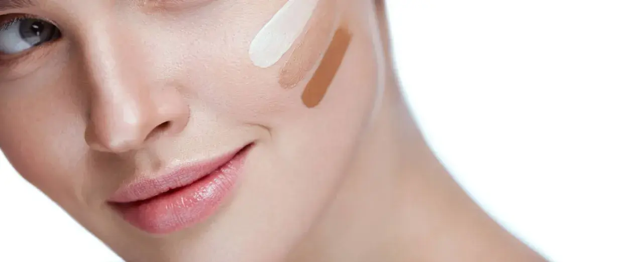 Prueba de tonos de corrector en la mejilla de una mujer.