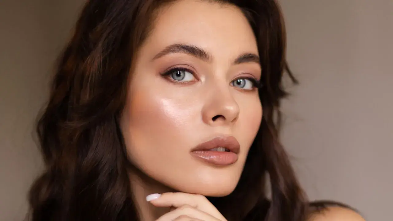 Primer plano de una mujer con cabello castaño oscuro y ojos azules. Su piel luce radiante, resaltando la belleza natural de la melanina.