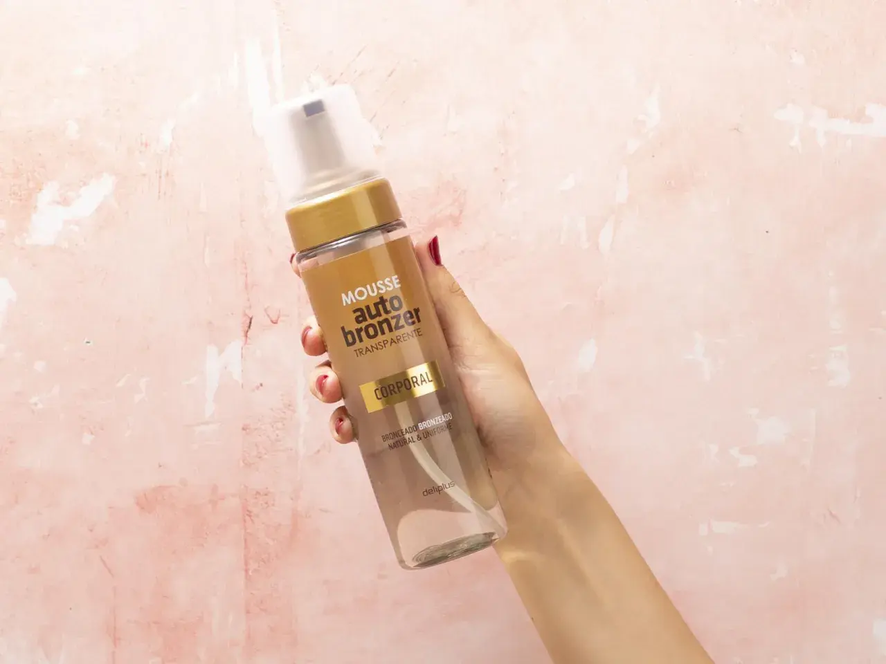 Mano sostiene botella de mousse autobronceador Deliplus de Mercadona. Bronceado natural y uniforme.