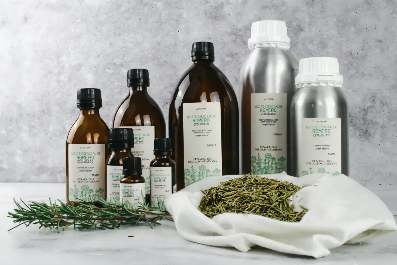 Aceites esenciales de romero en frascos de vidrio y metal, con ramitas frescas y romero seco. El aroma de linalool impregna la escena.