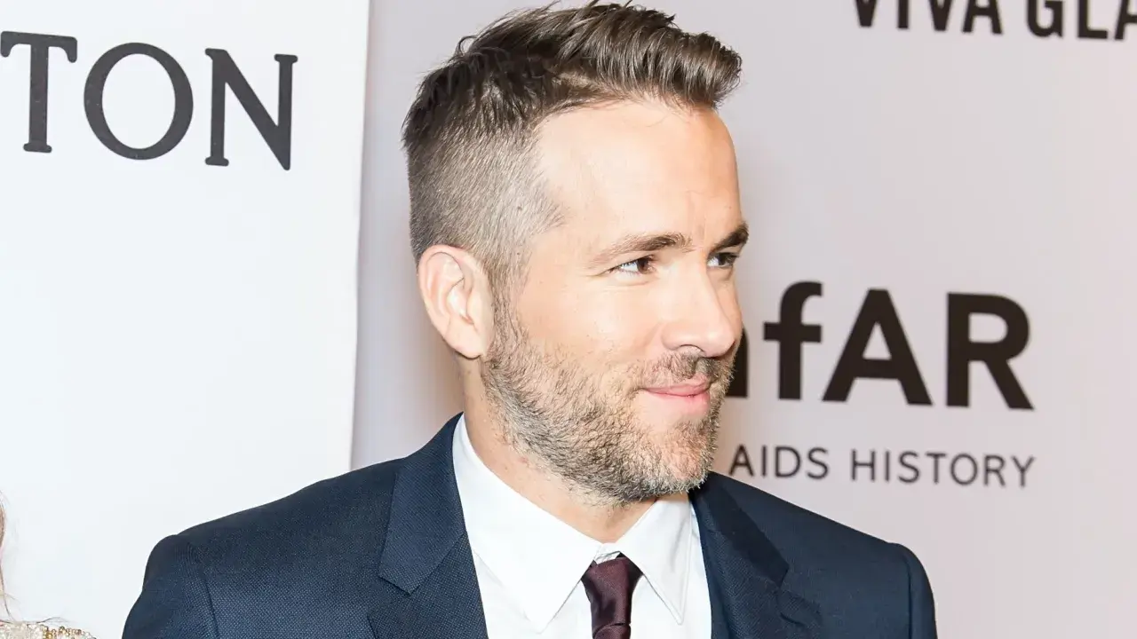 Ryan Reynolds luce un corte de pelo moderno con degradado hombre, barba cuidada y traje oscuro.