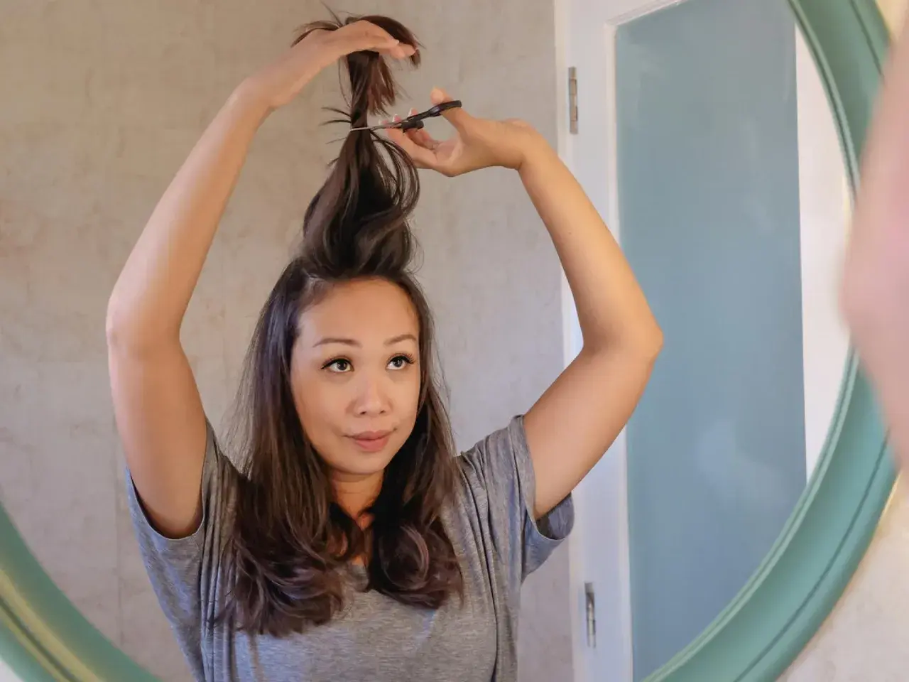 Mujer se corta el pelo en casa, creando un corte de pelo a capas.