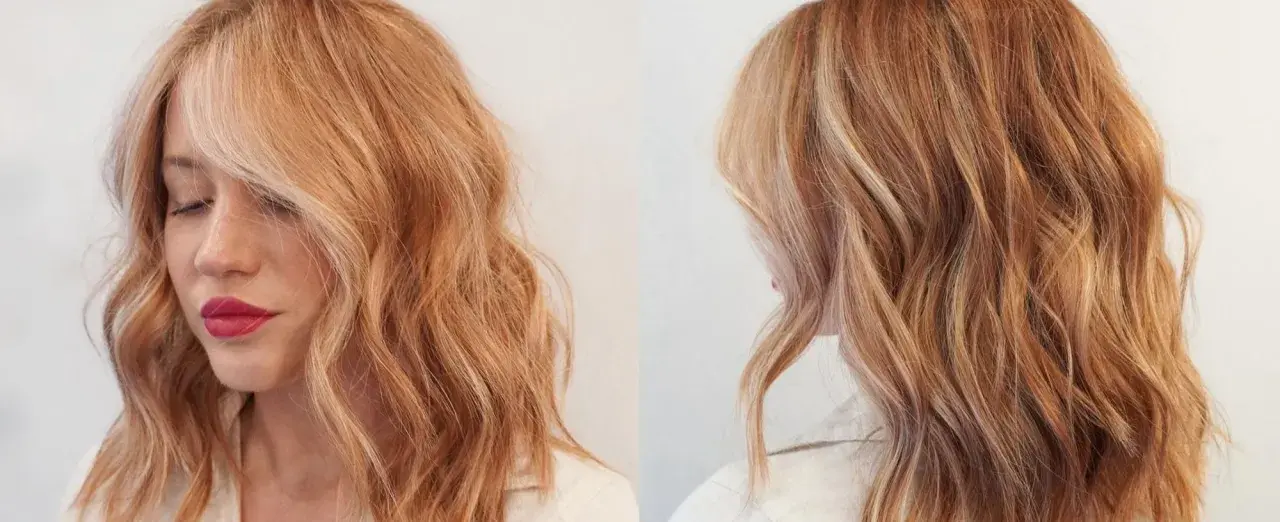 Mujer con cabello ondulado rubio fresa con reflejos dorados y rosados.