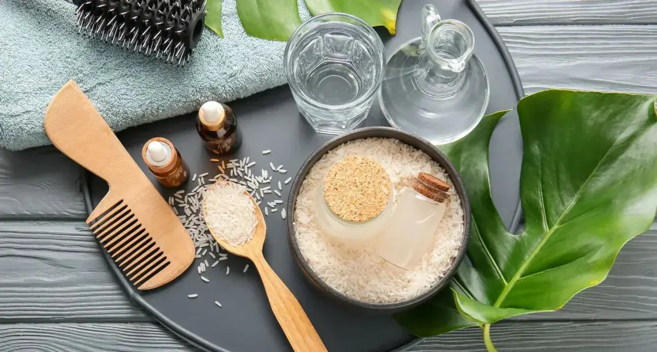 Ingredientes para un tratamiento capilar: arroz, agua de arroz, aceites y peine.