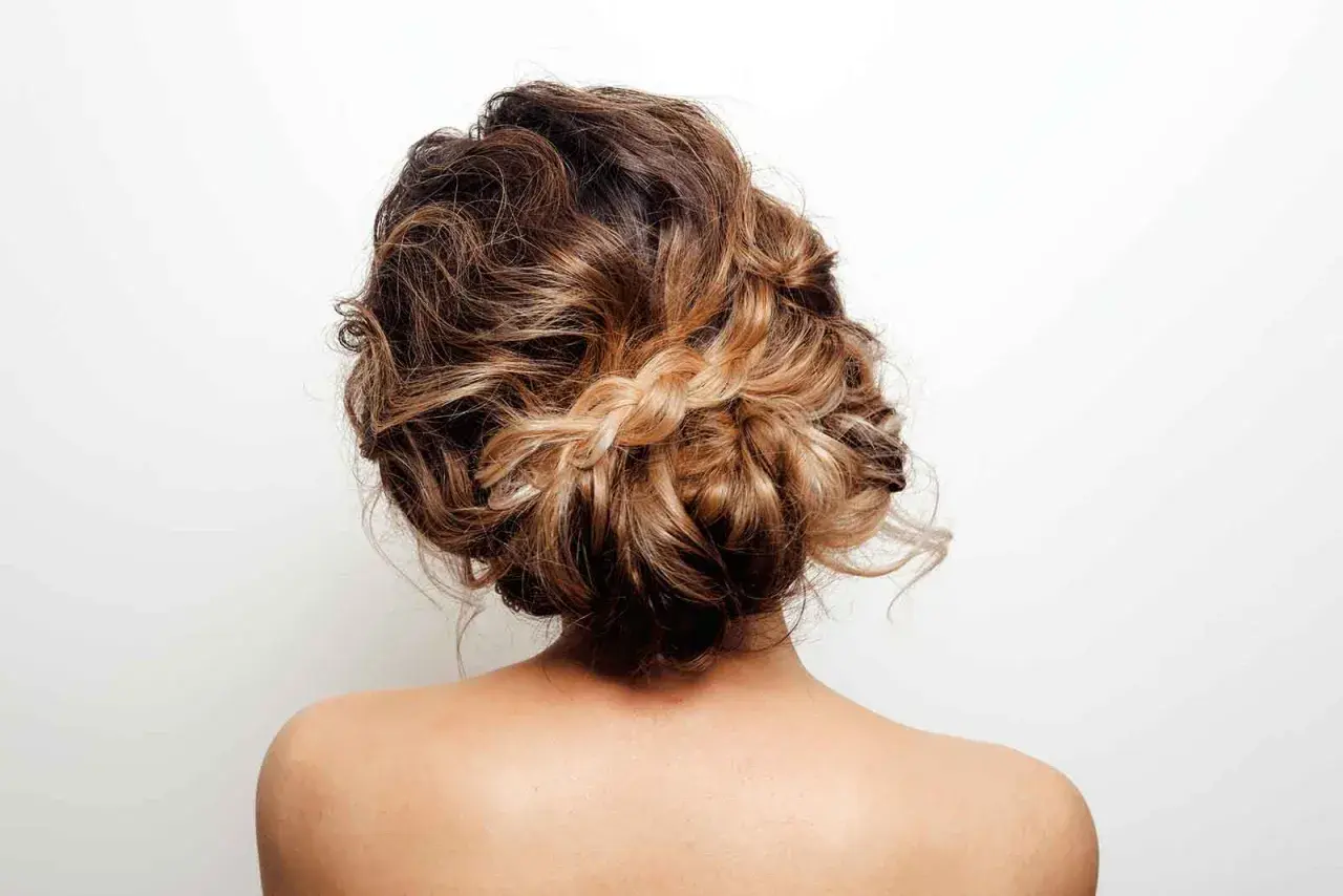 Recogido pelo rizado informal con trenza central, ideal para un look desenfadado y chic.