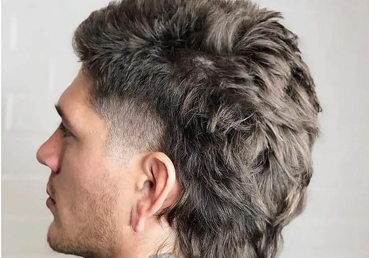 Perfil de hombre con pelo oscuro, rapado a los lados y largo en la nuca, un estilo moderno y atrevido.